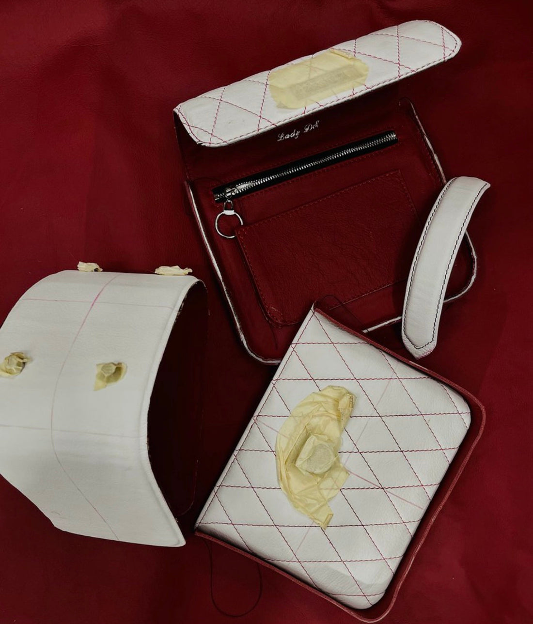 Maßgefertigte Tasche aus weißem Vollleder mit rotem Innenleder. Die Tasche ist geöffnet und in Einzelteilen dargestellt, mit Steppnähten, ein Unikat aus dem Atelier LANA DIESER.