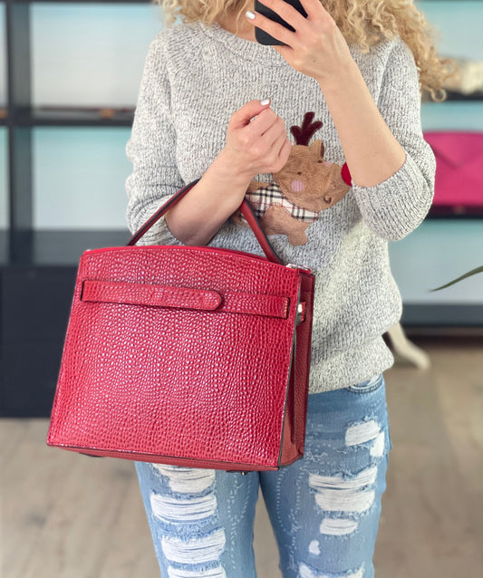 Rote Ledertasche CAVERA in Kroko-Optik, getragen an der Hand – zeigt die elegante Größe und Form im Alltagseinsatz.